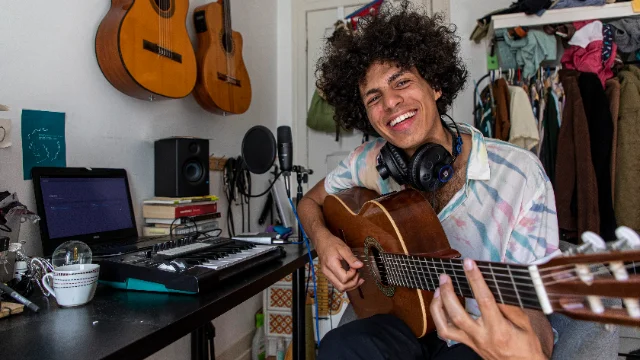 Armel Harlow playing guitar in a home studio